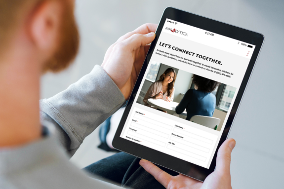 A man is about to fill out a contact form on the Analytica website while on a tablet.